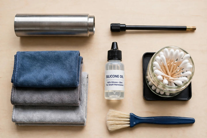 Airsoft cleaning supplies flat lay on a workbench with a barrel tube, cleaning rod, cloths and oil